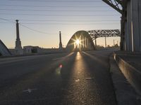 a train moving on a bridge at sunrise over the street and cars driving on the road