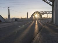 a train moving on a bridge at sunrise over the street and cars driving on the road