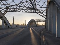 a train moving on a bridge at sunrise over the street and cars driving on the road