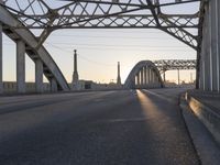 a train moving on a bridge at sunrise over the street and cars driving on the road