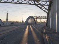 a train moving on a bridge at sunrise over the street and cars driving on the road