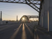 a train moving on a bridge at sunrise over the street and cars driving on the road