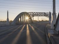 a train moving on a bridge at sunrise over the street and cars driving on the road