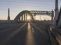 a train moving on a bridge at sunrise over the street and cars driving on the road