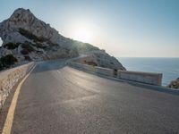 the sun is setting on a large hill overlooking a mountain slope with the road going up it