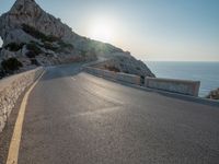 the sun is setting on a large hill overlooking a mountain slope with the road going up it