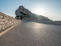 the sun is setting on a large hill overlooking a mountain slope with the road going up it