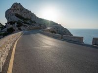 the sun is setting on a large hill overlooking a mountain slope with the road going up it