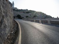 a motorcycle riding down an empty road next to a cliff on a sunny day in summer