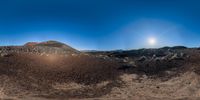 there is a large field full of dirt and rocks with the sun rising over a mountainside