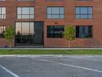 an empty street in front of a large red brick building on the other side of the road is a street light that has a line for motorists