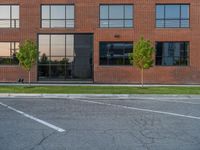 an empty street in front of a large red brick building on the other side of the road is a street light that has a line for motorists