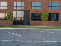 an empty street in front of a large red brick building on the other side of the road is a street light that has a line for motorists