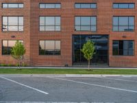 an empty street in front of a large red brick building on the other side of the road is a street light that has a line for motorists