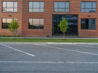 an empty street in front of a large red brick building on the other side of the road is a street light that has a line for motorists