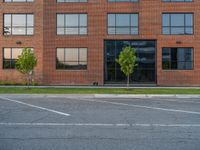 an empty street in front of a large red brick building on the other side of the road is a street light that has a line for motorists