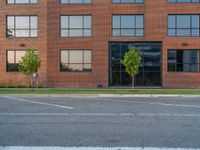 an empty street in front of a large red brick building on the other side of the road is a street light that has a line for motorists