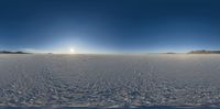 a large body of water in front of a sun shining over a vast landscape with snow