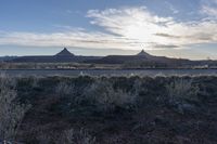 an outback area with a mountain in the distance, and plants around it with sparse bushes