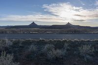 an outback area with a mountain in the distance, and plants around it with sparse bushes