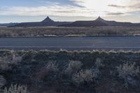 an outback area with a mountain in the distance, and plants around it with sparse bushes