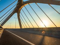 the sun rising behind a bridge across a highway, just after sunrise or sunset time