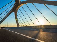 the sun rising behind a bridge across a highway, just after sunrise or sunset time