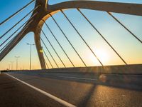 the sun rising behind a bridge across a highway, just after sunrise or sunset time