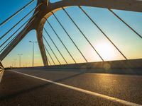 the sun rising behind a bridge across a highway, just after sunrise or sunset time