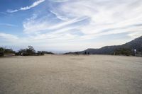 there are two people riding horses in the dirt area of a field in the mountain