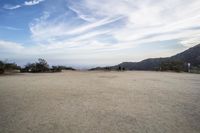 there are two people riding horses in the dirt area of a field in the mountain