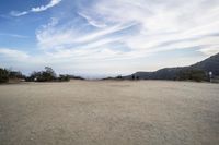 there are two people riding horses in the dirt area of a field in the mountain