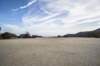 there are two people riding horses in the dirt area of a field in the mountain