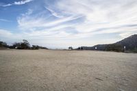 there are two people riding horses in the dirt area of a field in the mountain