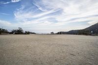 there are two people riding horses in the dirt area of a field in the mountain