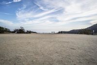 there are two people riding horses in the dirt area of a field in the mountain