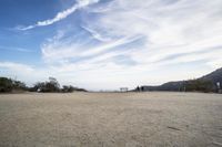 there are two people riding horses in the dirt area of a field in the mountain