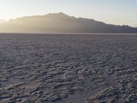 the sun rises over a large field of salt on the horizon of a mountain range