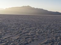 the sun rises over a large field of salt on the horizon of a mountain range
