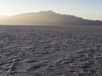 the sun rises over a large field of salt on the horizon of a mountain range