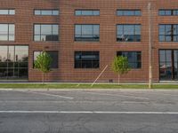 an empty street in front of a large red brick building on the other side of the road is a street light that has a line for motorists