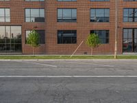 an empty street in front of a large red brick building on the other side of the road is a street light that has a line for motorists