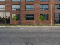 an empty street in front of a large red brick building on the other side of the road is a street light that has a line for motorists