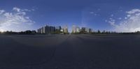 a wide angle shot shows a skyline from a parking lot with a skateboard on it