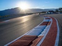 a photo of a dirt race track with sun setting in the distance of the track