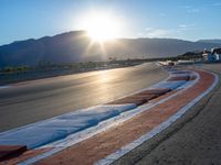 a photo of a dirt race track with sun setting in the distance of the track