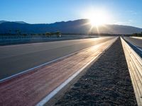 a photo of a dirt race track with sun setting in the distance of the track