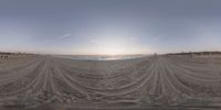 people are on the beach at sunset with sand in foreground as the sun shines behind