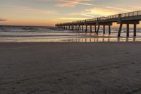 a sunset on a beach next to a pier in the sand with a horse drawn traces in the sand