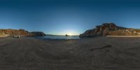 three motorcycles are parked on the beach near the water and cliffs at sunset time in a fish eye photo